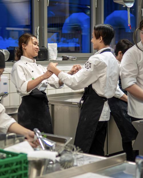 Bilde av elever på Restaurant og matfag som lager mat og danser på kjøkkenet - Klikk for stort bilde